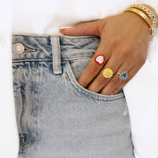 Hand in jeans wearing colorful heart-stone rings
