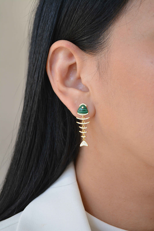 Mujer de perfil con un arete colgante en forma de pez con cabeza verde