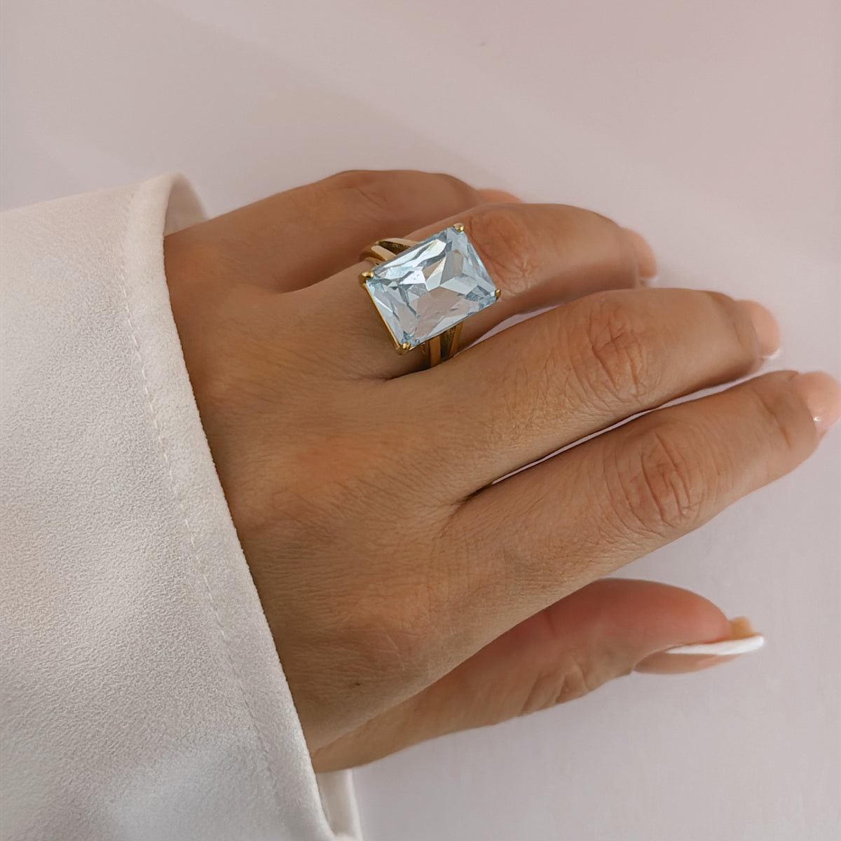 Hand wearing a ring with a large rectangular light blue stone