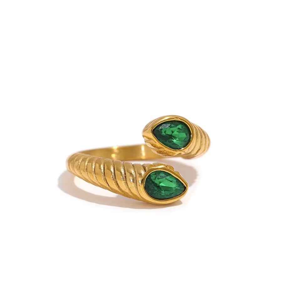 Anillo abierto acanalado de color dorado que termina en dos piedras verdes en forma de gota