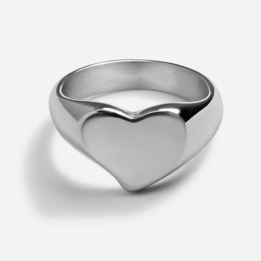 Smooth silver heart-shaped ring with a minimalist design, set against a clean white background with a soft shadow.