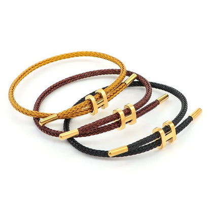 A product photo of three adjustable bracelets stacked together. The bracelets are made of braided rope in earthy and neutral tones: a golden-yellow, a dark reddish-brown, and a black. Each bracelet features a polished gold-toned metal clasp in the shape of a capital 'H' that can be adjusted for size. The set is displayed on a white background.