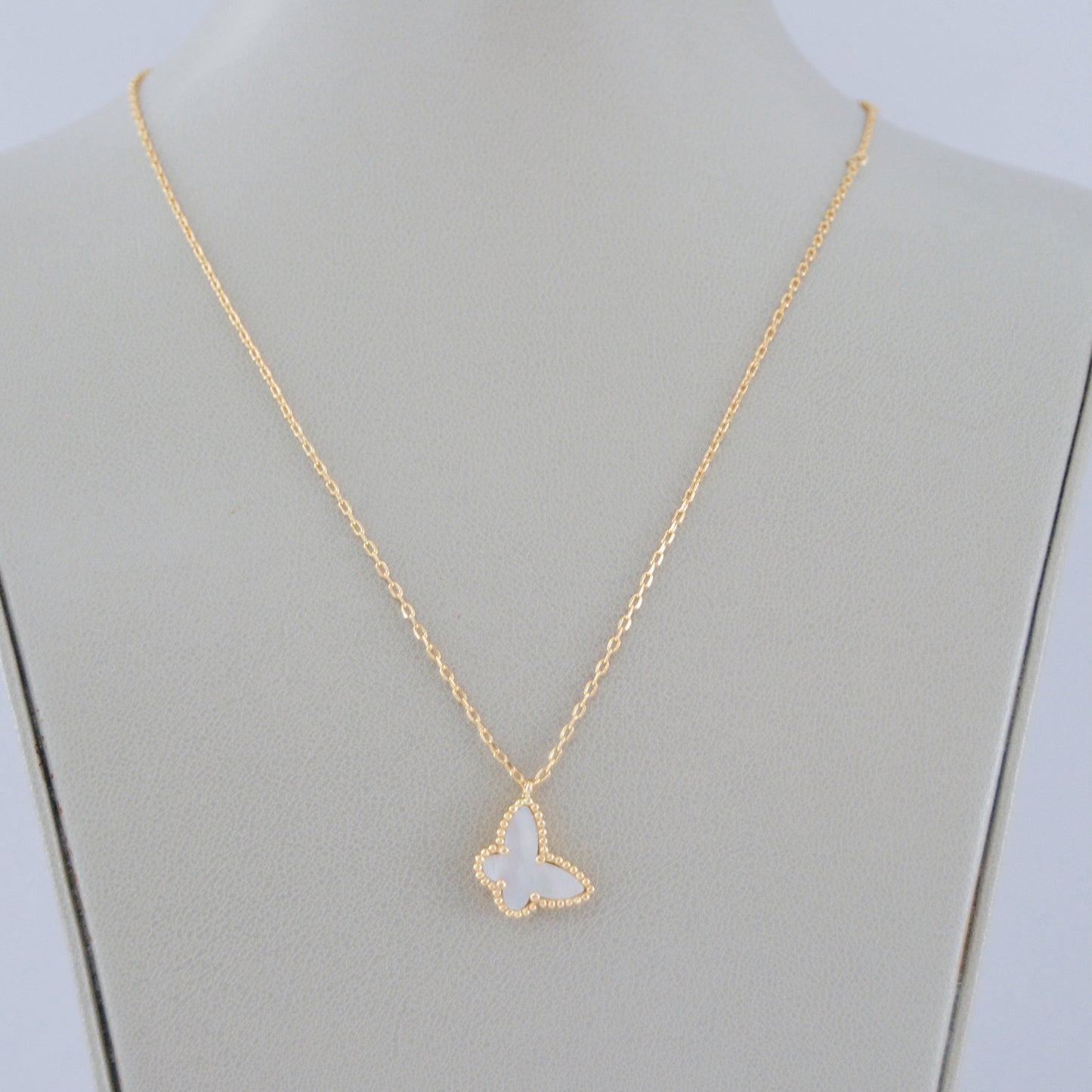Gargantilla de oro laminado con dije de mariposa blanca de madreperla. Collar delicado, ideal para layering y uso diario.