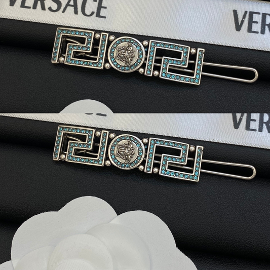 Two snap hair clips in aged silver-tone with a Greek key pattern, light blue stones and a round center medallion