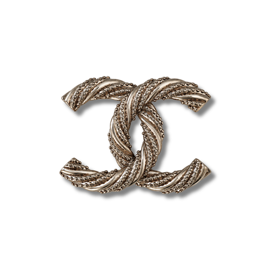 Broche tono plateado antiguo de doble curva entrelazada con textura de cuerda torcida, sobre fondo blanco