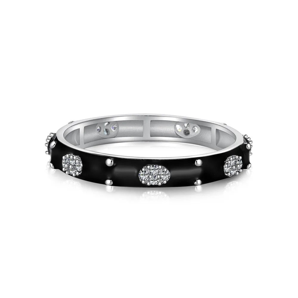 Anillo de esmalte negro con pequeños tachones y racimos ovalados de piedras brillantes alrededor de una banda de tono plateado