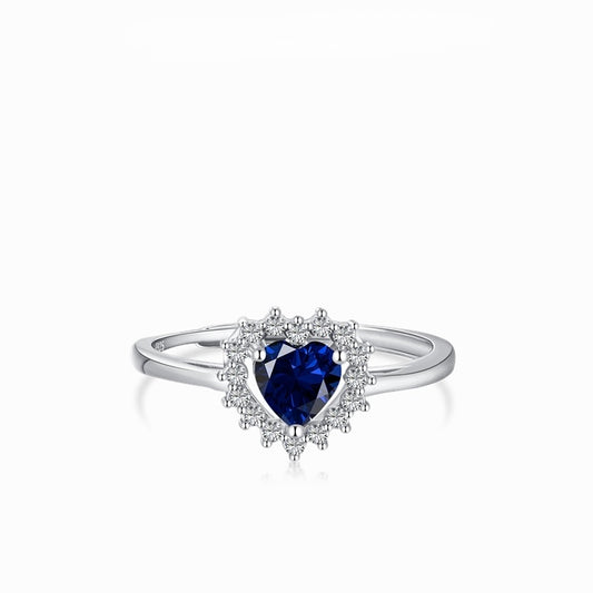 Anillo ajustable en tono plateado con una piedra azul intenso de corte corazón y un halo de piedras transparentes