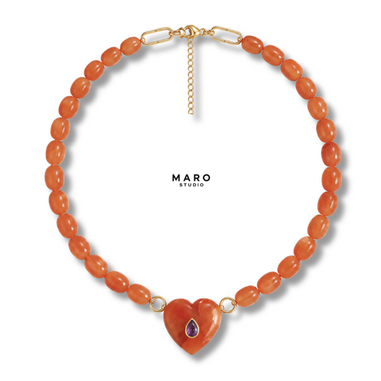Collar de cuentas ovaladas naranjas con un colgante de corazón naranja tallado y una pequeña piedra morada en forma de gota