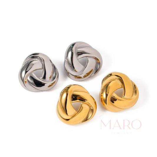 Two pairs of chunky polished knot earrings, two silver-tone and two gold-tone, on white