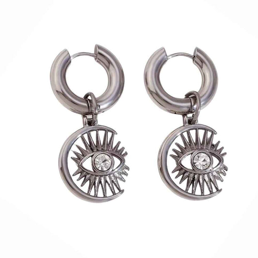 Pair of chunky silver-color huggie hoops with crescent charms framing an eye and a clear stone