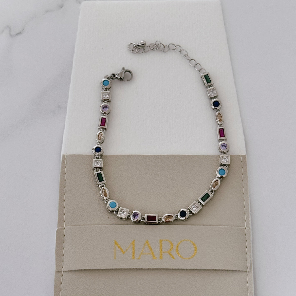 Colorful stone bracelet laid on a soft beige MARO pouch