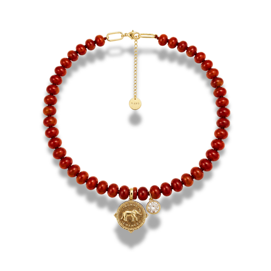 Deep red bead necklace with a gold-tone coin charm and a small clear stone, with an extender chain