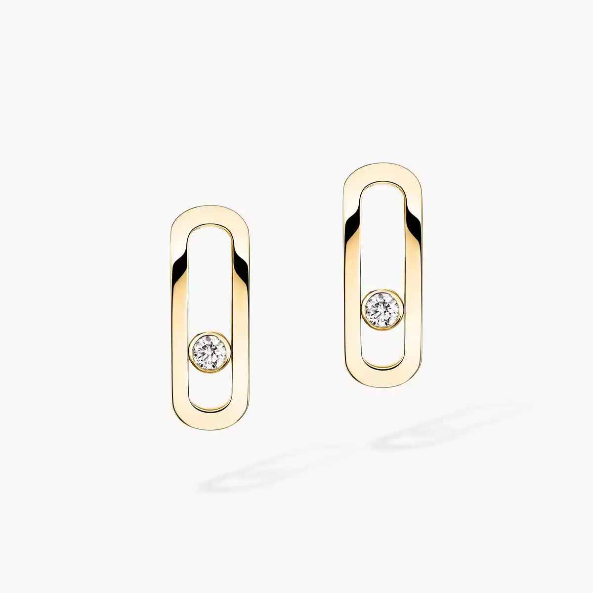 Pair of elongated open oval earrings in pale gold-tone, each with a small stone inside the frame, on light background