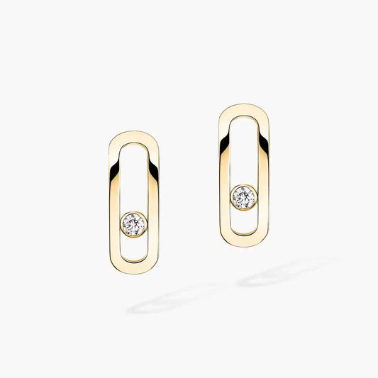 Pair of elongated open oval earrings in pale gold-tone, each with a small stone inside the frame, on light background