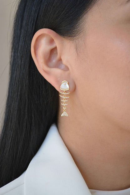 Mujer de perfil con un arete colgante largo en forma de pez con cabeza clara