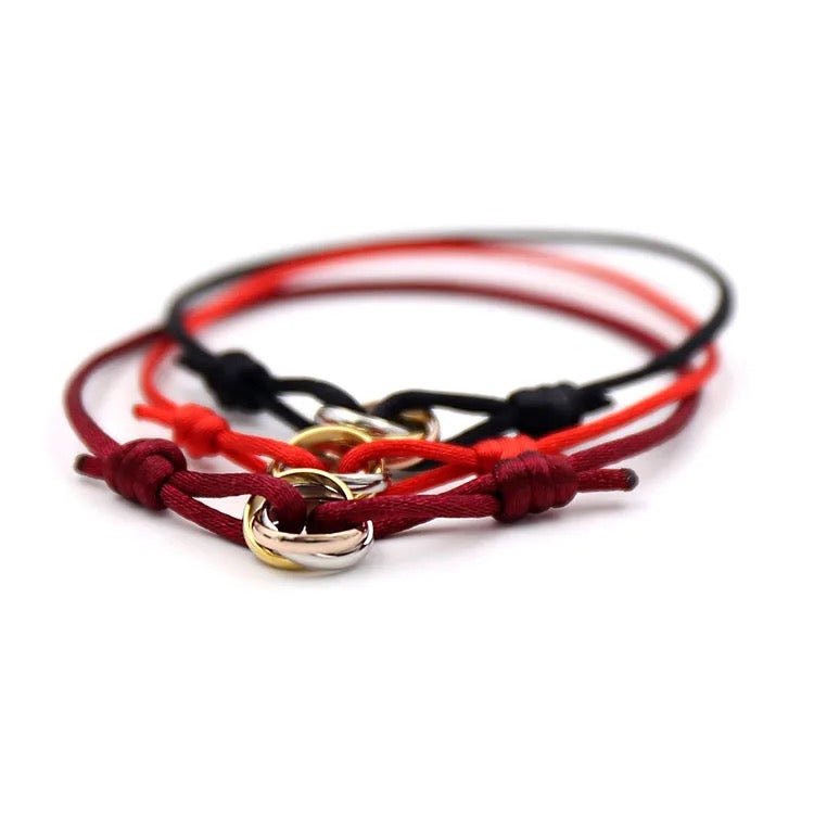 Pila de pulseras de cordón rojas y naranjas con pequeños anillos entrelazados