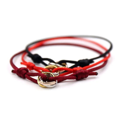 Pila de pulseras de cordón rojas y naranjas con pequeños anillos entrelazados