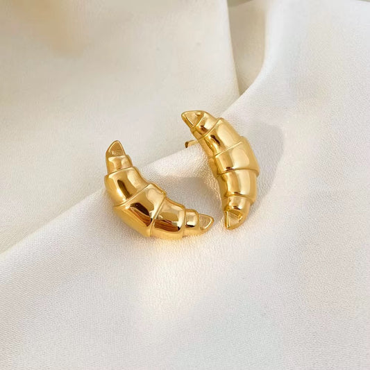 Par de aretes de croissant brillantes color dorado sobre tela color crema