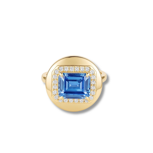 Gold-tone ring with a rectangular blue stone framed by a halo of small clear stones