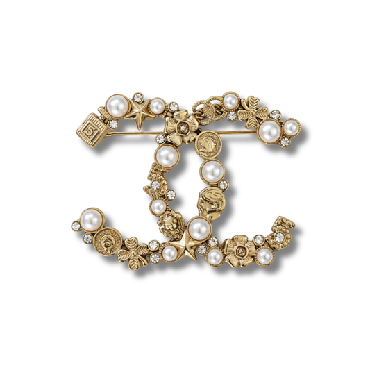 Broche tono dorado de doble curva entrelazada con pequeñas flores, estrellas y perlas color crema
