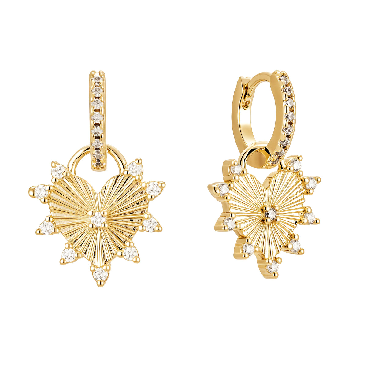 Pair of gold-tone huggie hoops with sunburst-style heart charms and small clear stones, on white