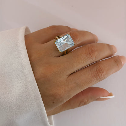 Hand wearing a ring with a large rectangular light blue stone