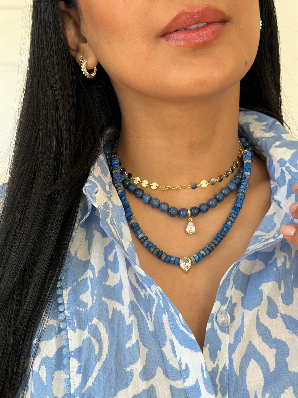 Woman wearing layered blue beaded necklaces with a small gold-tone detail at the neck