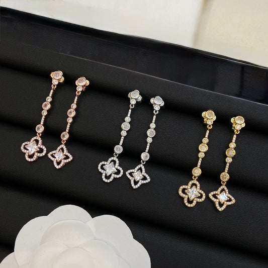Three pairs of long drop earrings with linked small stones ending in a four-petal flower, in rose, silver-tone and gold-tone
