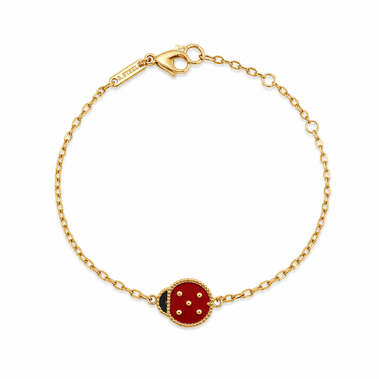 Fine gold-tone chain bracelet with a red ladybug charm and a lobster clasp