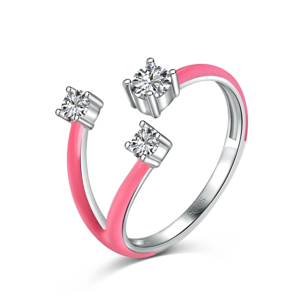 Anillo abierto de tono plateado con extremos de esmalte rosa y tres piedras transparentes engastadas en la abertura