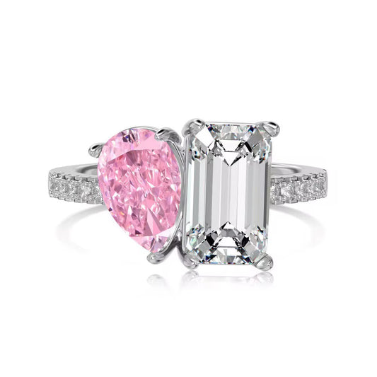 Pink zirconia ring with a pear-shaped pink stone and a clear emerald-cut stone, front view on white