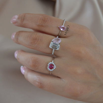 Mano con tres anillos, uno con una piedra rosa en forma de pera y otro con una piedra cuadrada transparente
