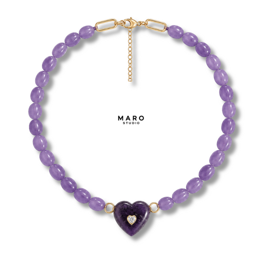 Collar de cuentas ovaladas moradas con un colgante de corazón morado liso y una pequeña piedra blanca en el centro