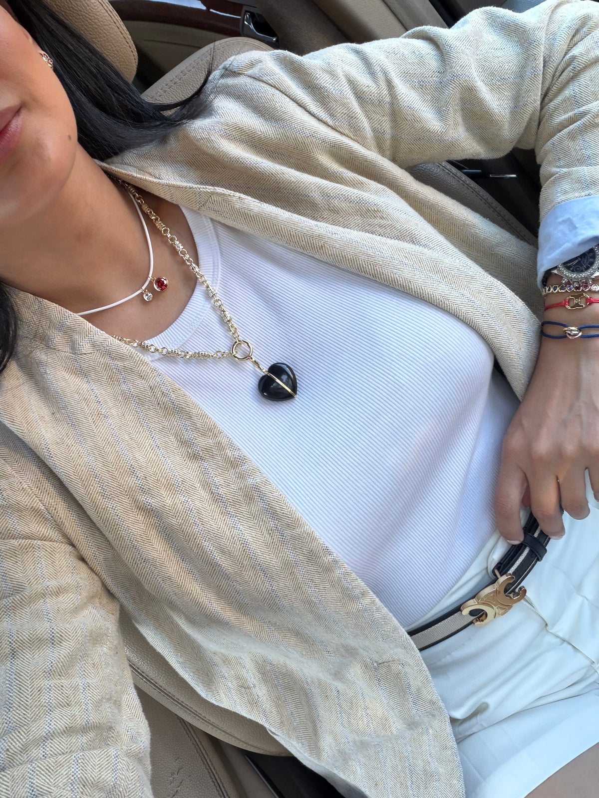 Mujer con camiseta blanca y chaqueta de lino que lleva un collar en capas con un colgante oscuro