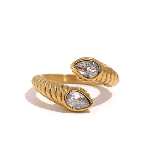 Anillo abierto acanalado de color dorado que termina en dos piedras transparentes en forma de gota
