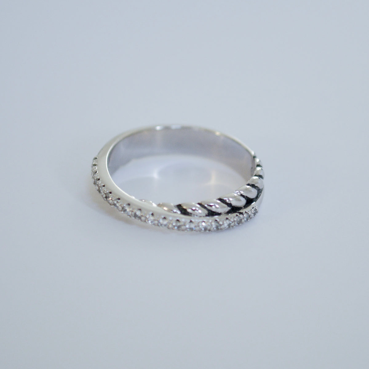 Silver-tone crossover ring with one twisted rope-style side and one side lined with small clear stones