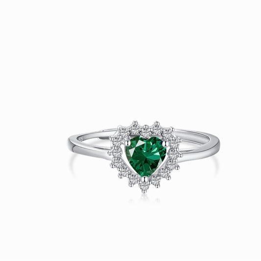 Anillo en tono plateado con una piedra verde de corte corazón rodeada de pequeñas piedras transparentes