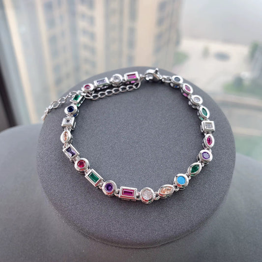 Silver-tone chain bracelet with multicolor stones on a gray display stand