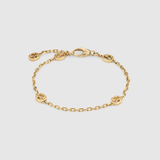 Pulsera delgada de cadena tono dorado con pequeños eslabones redondos con emblema repartidos y cierre de langosta