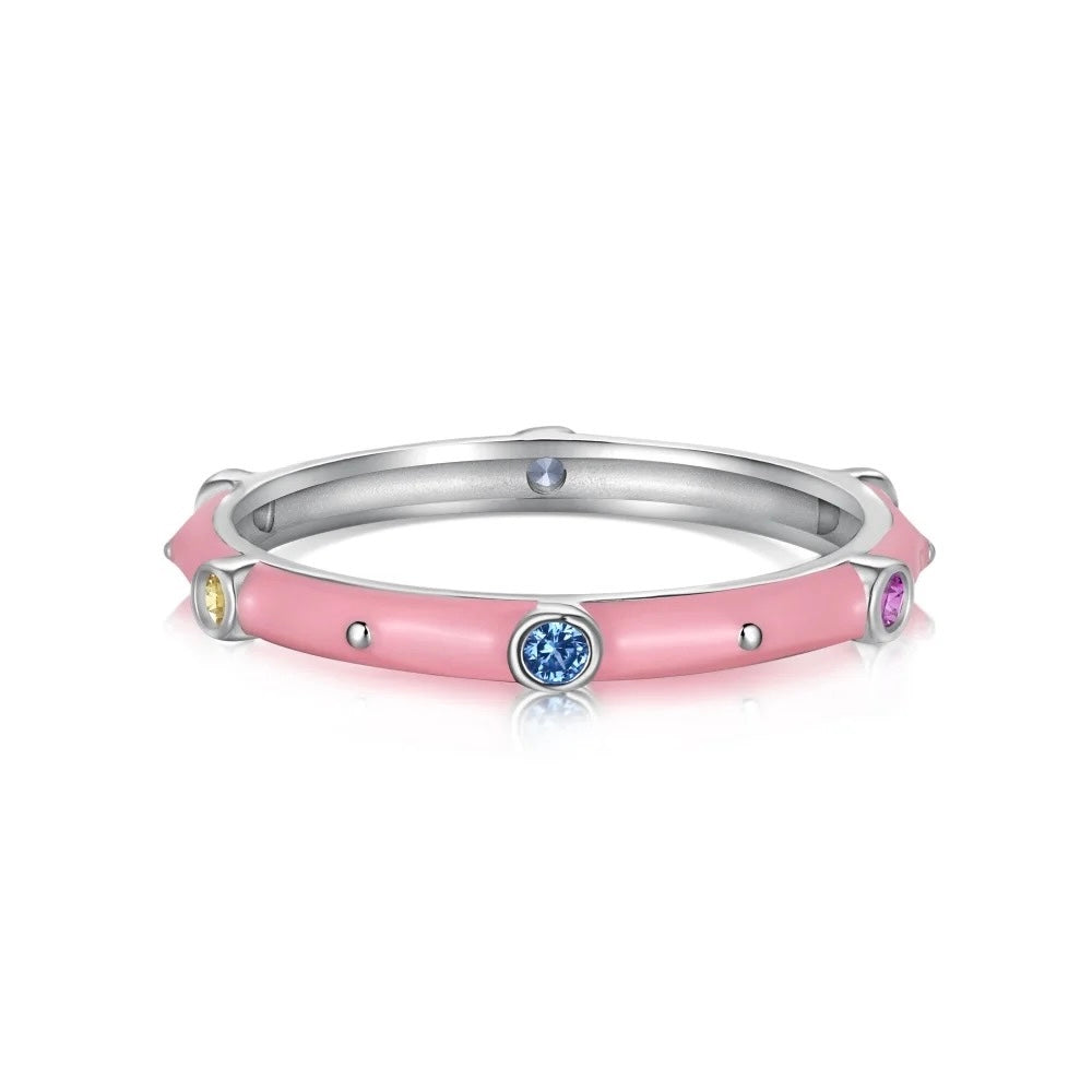 Anillo delgado de esmalte rosa con pequeñas piedras redondas azules, amarillas y moradas alrededor de una banda de tono plateado