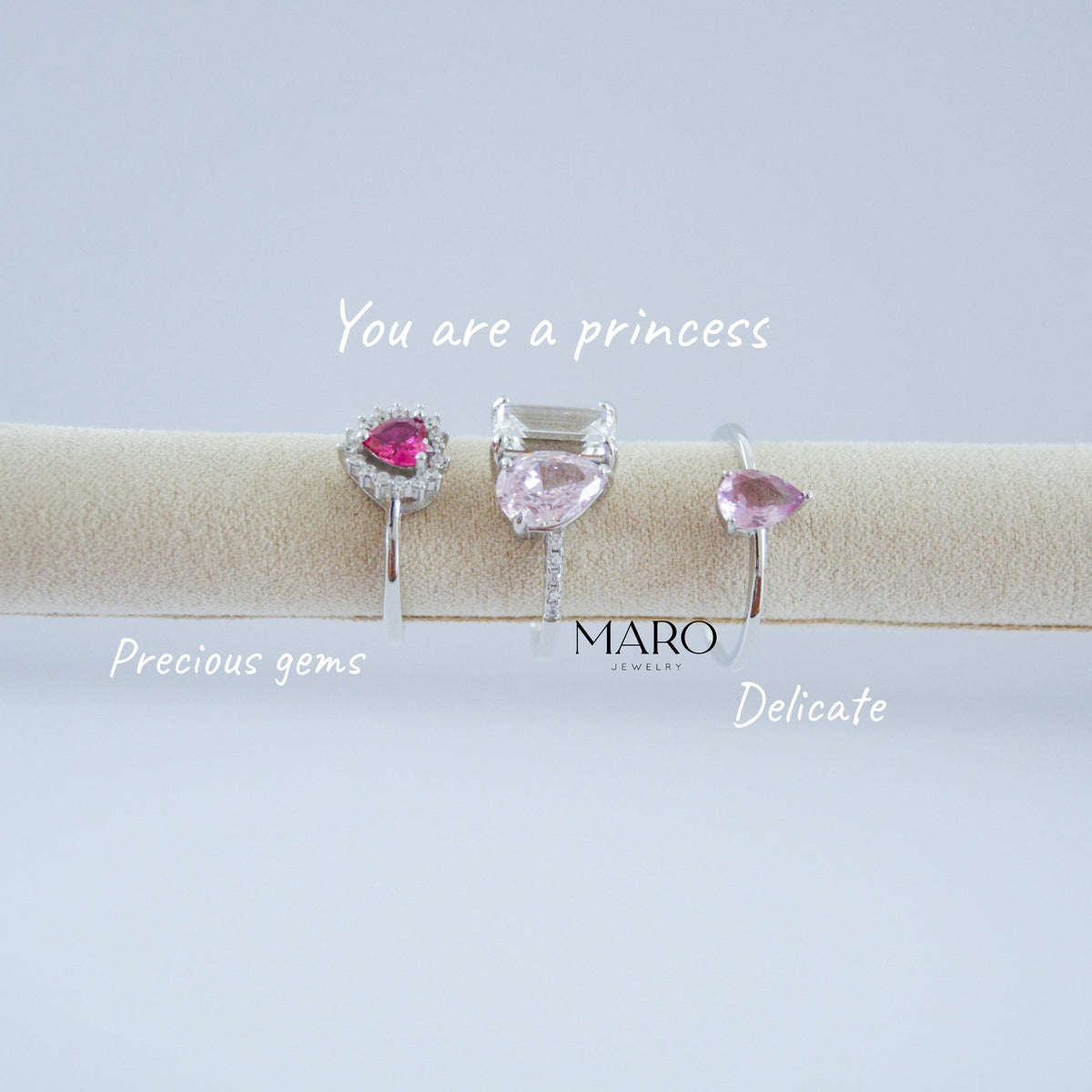 Tres anillos pequeños con piedras rosas sobre un rollo beige con las palabras You are a princess
