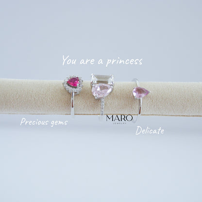 Tres anillos pequeños con piedras rosas sobre un rollo beige con las palabras You are a princess