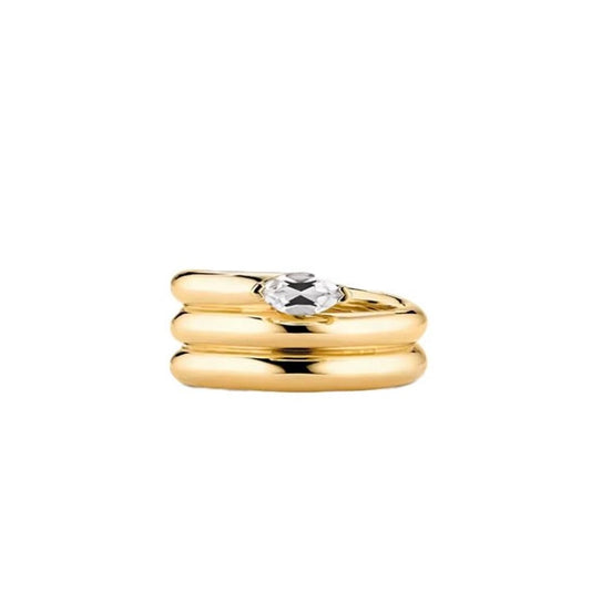 Three stacked gold-tone bands forming one ring, with a pointed oval clear stone on top, on white