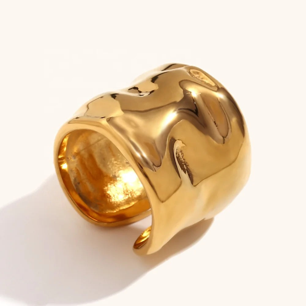 Anillo ancho color dorado con una superficie ondulada martillada