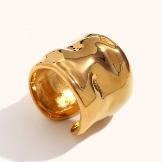 Anillo ancho color dorado con una superficie ondulada martillada