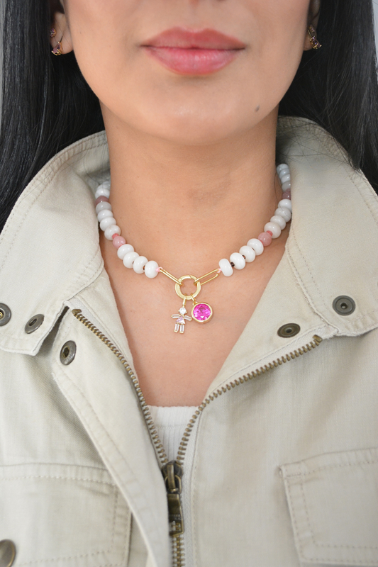 Woman in a cream jacket wearing a white and pink bead necklace with a small pink charm