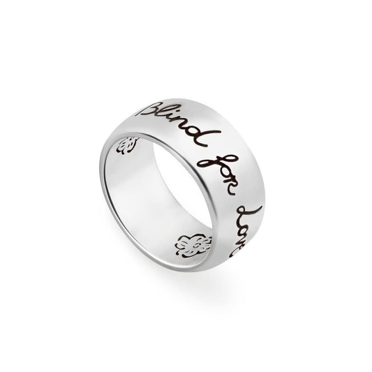 Wide silver-tone ring with handwritten-style lettering engraved around the band, on white